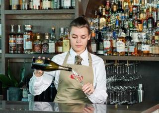 waitress pouring champagne into glass at bar