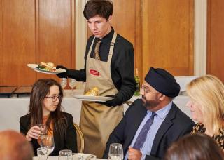 waiter serving food to guests at table